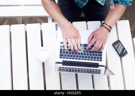 Looking down on male using laptop on white table Stock Photo