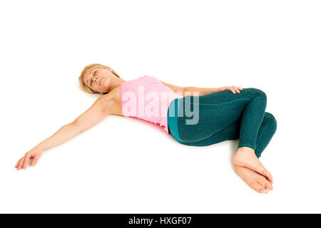 Side full body view of a lying on the ground young woman in yoga position 'Crocodile' (Nakrasana) on a white background with side far outstretched arm Stock Photo