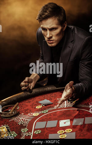 Emotional man in suit sitting at poker table and gesturing Stock Photo