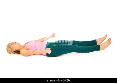 Flat angular body side view of a lying on the back girl in variation of the 'Dead position' Yoga position (shavasana) on a white background. Stock Photo