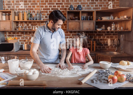 'Happy father and daughter cooking together and looking at each other in kitchen Stock Photo