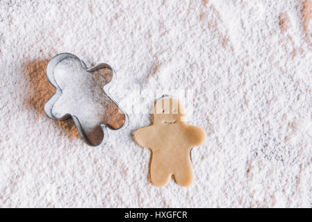 'Close-up view of uncooked gingerbread man and cookie cutter on flour Stock Photo