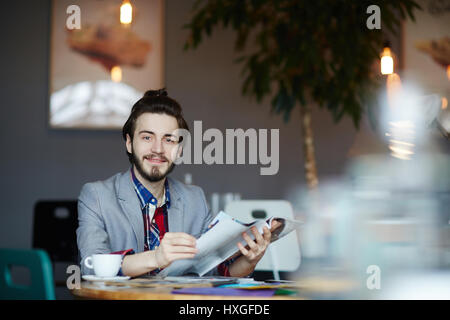 Young man with journal sitting in cafe at coffee-break Stock Photo