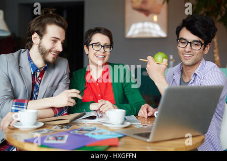 Happy designers looking at online data on laptop monitor Stock Photo