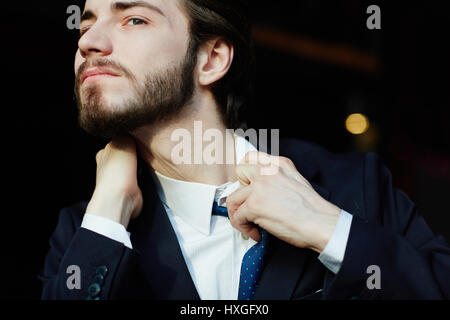 Portrait of young bearded businessman tearing away the tie and shirt trying to get some air, having trouble breathing and suffocating from stress Stock Photo