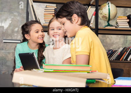 Three smiling children using digital tablet in library Stock Photo