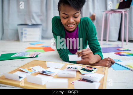 Girl lying on the floor of design-studio and looking through photos Stock Photo