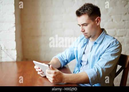 Side view portrait of modern young man using portable digital tablet and looking at screen Stock Photo