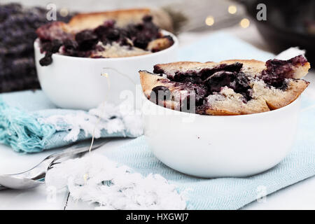Two bowls of freshly baked homemade blueberry lavender cobbler. Selective focus on dish in foreground with extreme shallow depth of field. Perfect des Stock Photo