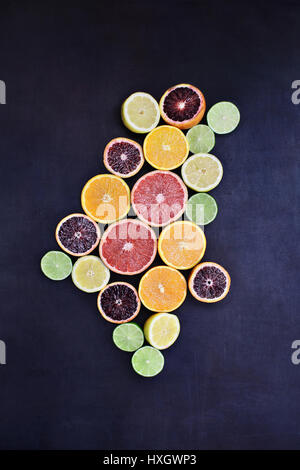 Variety of citrus fruits (orange, blood oranges, lemons, grapefruits, and limes) over a black rustic background. Image shot from overhead. Stock Photo