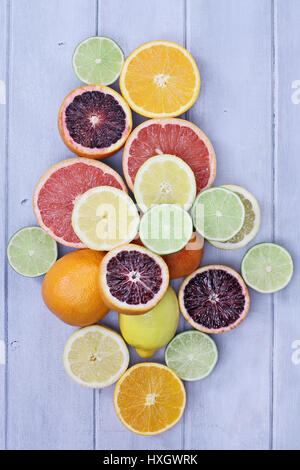Variety of citrus fruits (orange, blood oranges, lemons, grapefruits, and limes) over a blue wood table top rustic background. Image shot from overhea Stock Photo