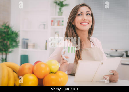 Beautiful young woman in the kitchen drinking coffee and thinking. Stock Photo