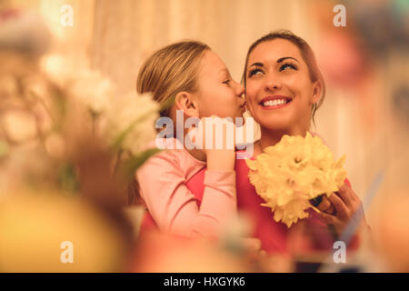 Cute little girl giving her mother bouquet yellow daffodils and kissing you. Stock Photo