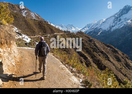 Trekker on a trail in the Himalayan region, with Everest and Ama Dablam mounts in the background Stock Photo