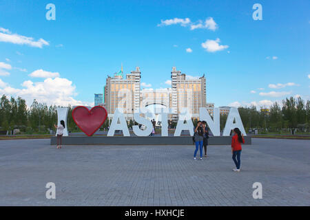 I love Astana - large letters, bacground KazMunaigas and blue sky, located in the city of Astana, the capital of Kazakhstan. People walking by city. Stock Photo