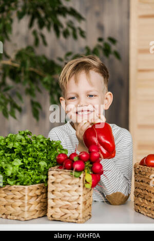 Handsome little boy in kitchen eating vegetables. Vegetarian. Healthy food Stock Photo