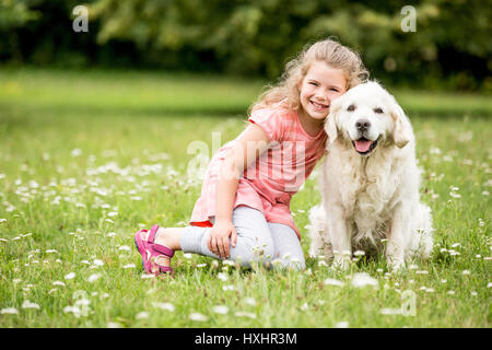 Girl and dog as friends happy together in summer in the nature Stock Photo