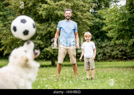 Dog juggles football with nose while playing with his family Stock Photo