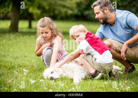 Children petting and playing with dog in summer at the park Stock Photo