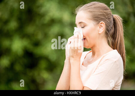 Woman with allergy or a cold sneezing with tissue