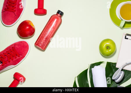 Fitness concept. Sneakers, apple, dumbbell and fruit juice bottle on pastel color background. Stock Photo