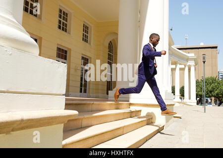 Full length portrait of young businessman running out of a building in the city Stock Photo