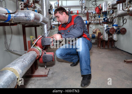 St. Petersburg, Russia - March 5, 2013: Technician maintenance repairman engineer inspecting heating system in boiler room. Stock Photo