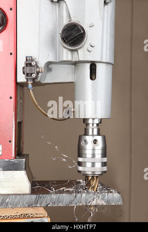 Drilling hole in metal, metalworking industry, drilling a hole on modern metal working machining center, metal hole saw bit. Stock Photo