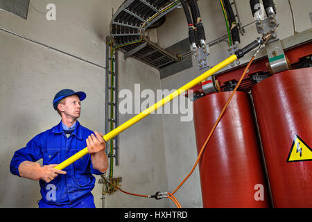 Electrical Engineer imposes temporary grounding on lowering power transformer, to ensure the safety of using an insulating rod. Stock Photo