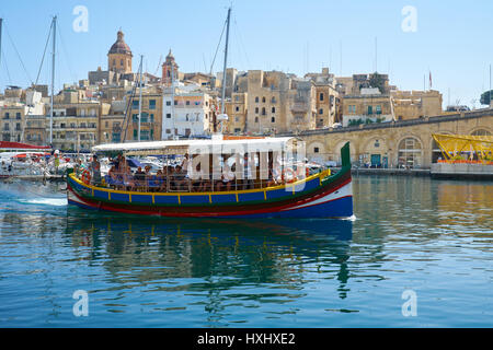 BIRGU, MALTA - JULY 23, 2015: The view of traditional Maltese boat Luzzu, serving as a walking  dinghy in Dockyard bay on the background of Birgu city Stock Photo