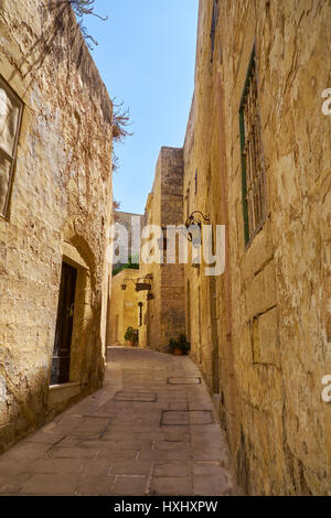 MDINA, MALTA - JULY 29, 2015: In the surroundings of limestone walls. The narrow medieval stone paved street of Mdina, the old capital of Malta Stock Photo