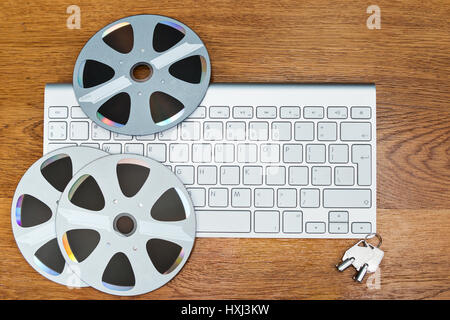 Compact disks in the form of old bobbins lie on the keyboard, on a wooden table next to the keys Stock Photo