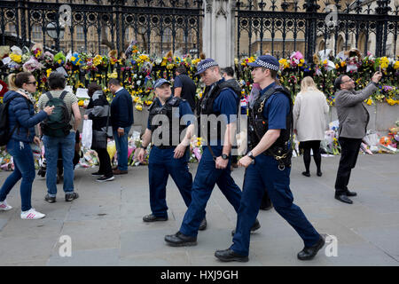 London, UK. 28th Mar, 2017. One week after the terrorist attack in the UK capital, Londoners and visitors to Britain look at the flower memorials left on Westminster Bridge (where pedestrians were mown down by a car) and outside the Palace of Westminster where armed police now guard the location where a police officer was killed. Credit: Richard Baker/Alamy Live News Stock Photo