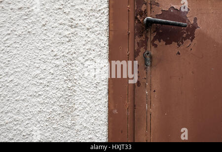 Closeup view on old metal doors and lock on one side and old white wall on other side. Stock Photo