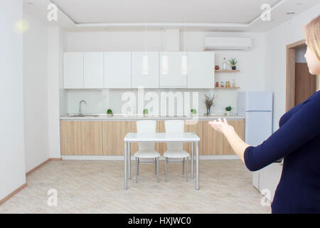 Real estate agent presenting modern house to client, woman Shows the kitchen. Stock Photo