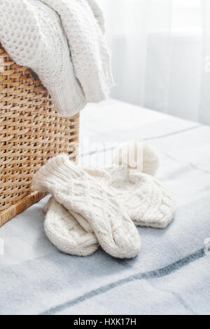 Rattan baskets with winter clothes and white mittens closeup Stock Photo