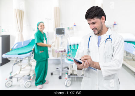 Doctor writing medical records in modern hospital room with beds and comfortable medical equipped Stock Photo