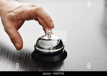 Male hand ringing in service bell on wooden table closeup Stock Photo