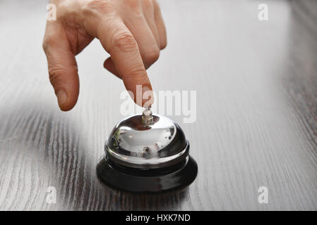 Male hand ringing in service bell on wooden table closeup Stock Photo