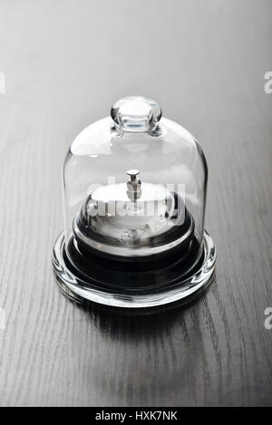Service bell in glass mini dome on wooden background Stock Photo
