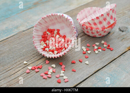 Color candy hearts with cupcake cases on wooden background Stock Photo