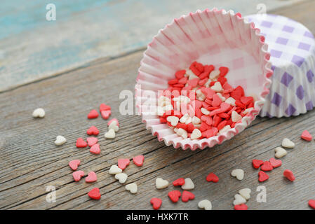 Color candy hearts with cupcake cases on wooden background Stock Photo