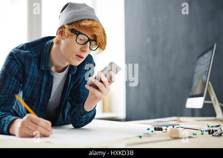 Creative Young Man Using Smartphone for Work Stock Photo