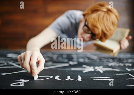 Young Scientist Writing on Blackboard in Class Stock Photo