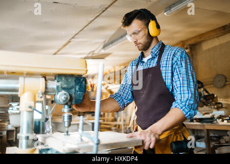 Drilling wooden board in workshop Stock Photo
