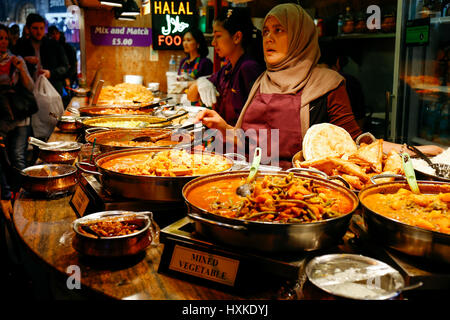 Traders at a market stall selling curry and varieties of cooked foods at Camden Market. Stock Photo