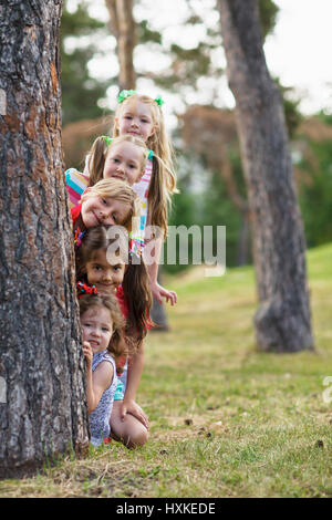 Friends hiding behind tree Stock Photo