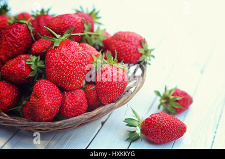 Strawberry in wicker plate on wooden background Stock Photo