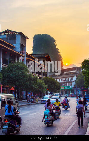 YANGSHUO, CHINA - SEPTEMBER 23 2016: Stunning sunset on the crowded Yangshuo street with karst formation in background Stock Photo