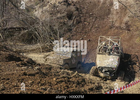 Dirty all-terrain vehicle is pulled from muddy trench uphill, anothet four-drive got stuck in a trench of mud at Offroad competition in Slovenia Stock Photo